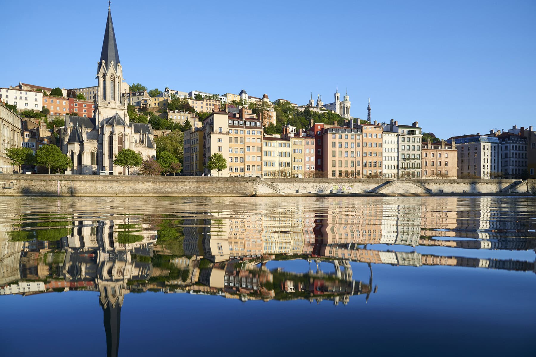 A calm river reflecting historic European buildings, viewed from a luxury river cruise.