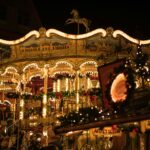 A beautifully lit historic carousel at the Christmas Market, surrounded by festive decorations and holiday lights.