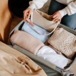 Woman packing soft sweaters and essentials in a suitcase.